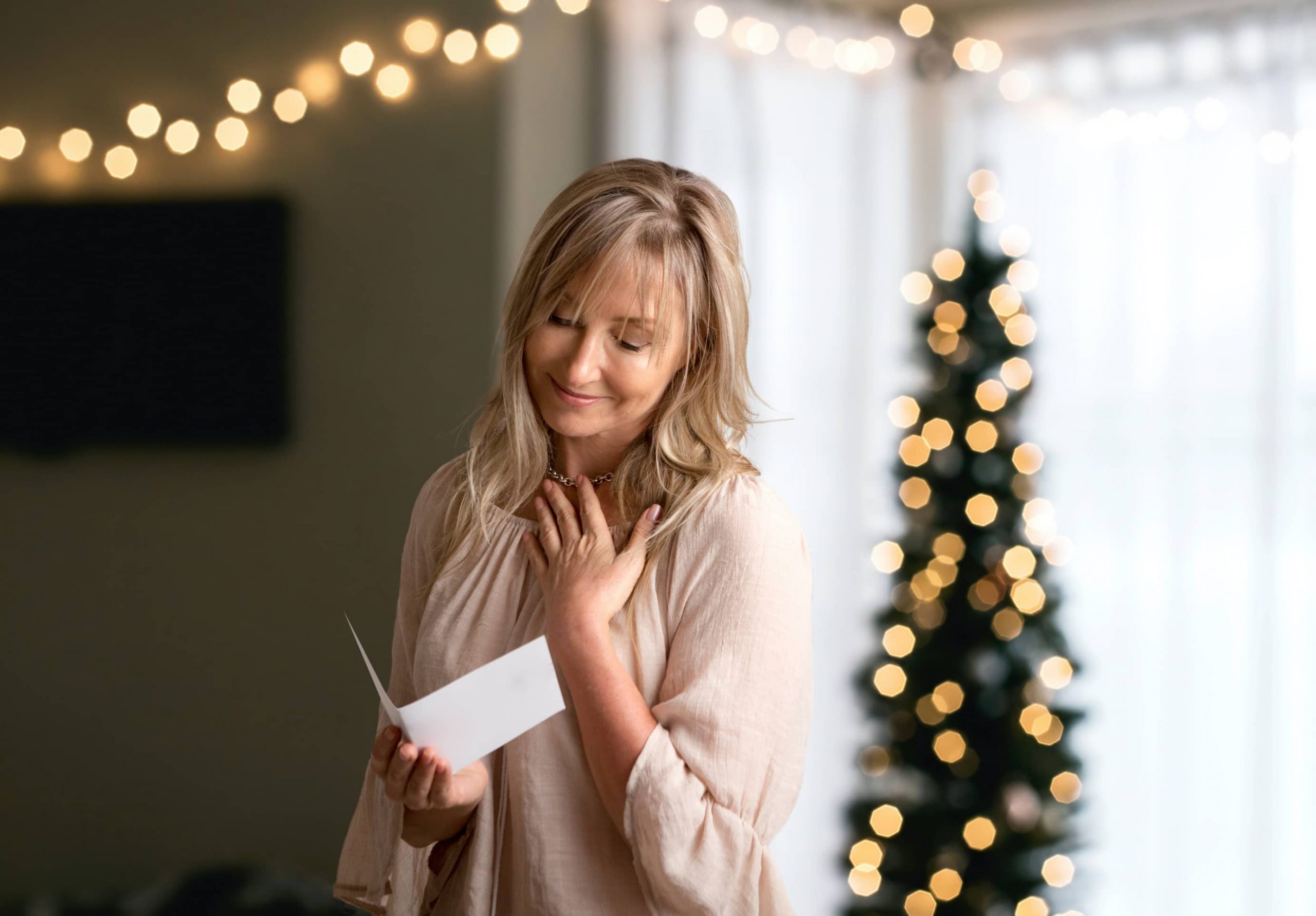 woman admiring handwritten letter in front of Christmas tree